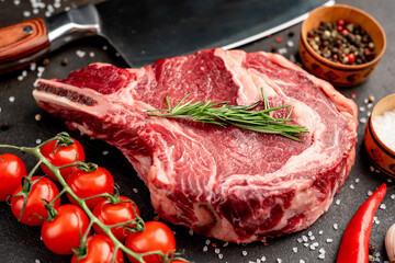 raw  ribeye steak with spices on a stone background