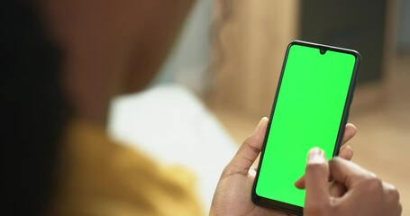 Close up of young african american woman using smartphone browsing news feed on social networks. Girl holding phone. Green screen. - Powered by Adobe