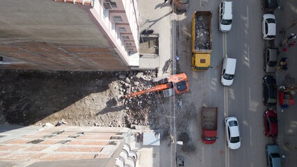 Aerial view of excavation work at the city center. Excavator is filling the land into the truck between buildings.  © abu