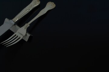 Lay out of vintage old silver cutlery. made in England. 
knife, fork on black background.  

Top view photo ・dim lighting soft focus image.