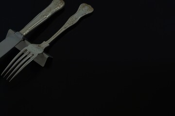 Lay out of vintage old silver cutlery. made in England. 
knife, fork on black background.  

Top view photo ・dim lighting soft focus image.
