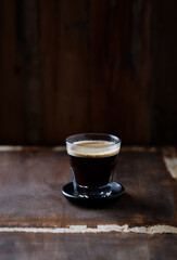 Coffee in glass cup on dark wooden background. 