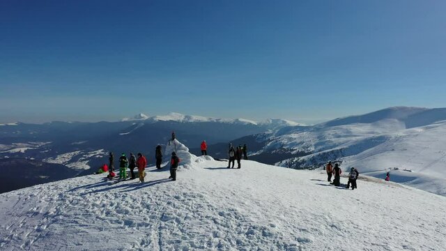 group of snowboarders at the top of the mountain are preparing to descend. sunny weather in high mountains, winter sports