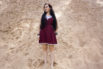 A girl stands on a sandy slope by the river