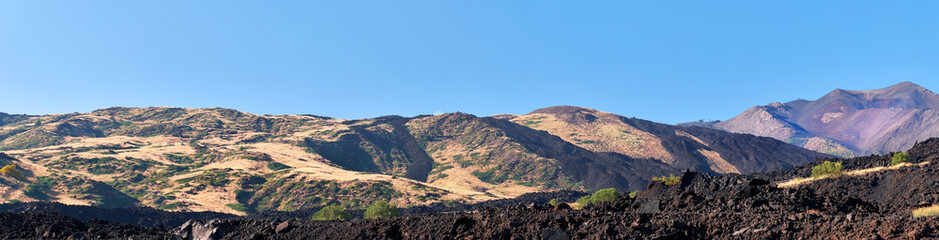 Naklejka premium Mount Etna in Sicily, Tallest active Europe volcano in Italy. Panoramic wide view of the active volcano Etna, volcanic ash and lava fields, traces of volcanic activity.
