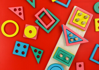 Multicolored wooden blocks on red blue background. Trendy puzzle toys. Geometric shapes: square, circle, triangle, rectangle. Educational toys for kindergarten, preschool or daycare. Back to school
