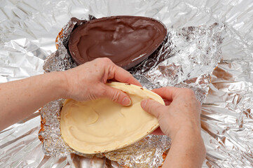 Easter Egg - Hands breaking homemade stuffed chocolate egg. Top view. Copy space