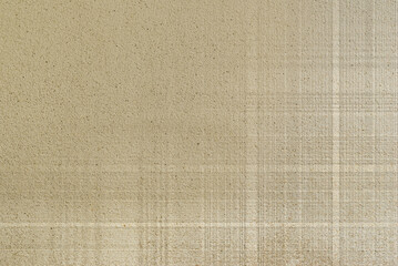 Fototapeta na wymiar Shadow of faded cross line pattern on rough concrete wall surface in earth tone color. 