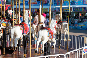 kids at an amusement park  rides a horse on a carousel in the summer