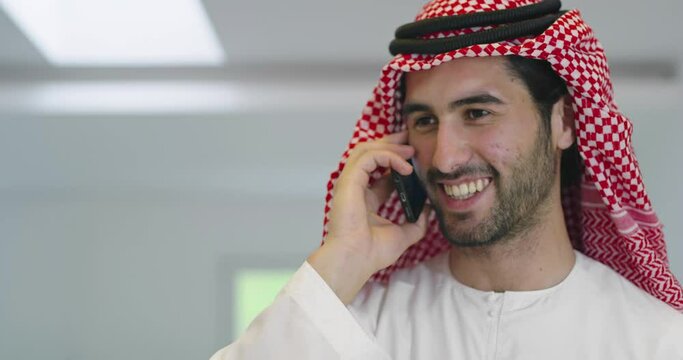 Arabian businessman wearing traditional clothes while using smartphone at home