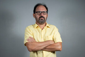 person dressed in yellow shirt with crossed arms in neutral background