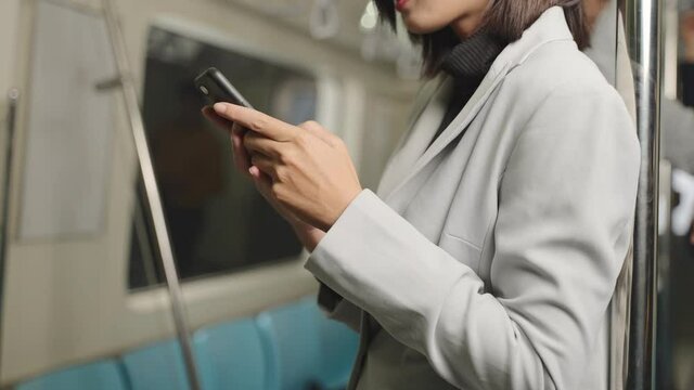 Asian female businessmen Reply to chat messages And use the phone on the skytrain or subway their way to working transportation. She discussion business on his phone while traveling to meet a partner.