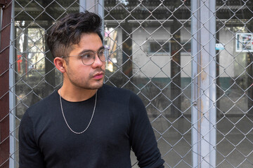 Chico posando recargado en una reja 