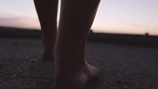 Barefoot Woman Walking Towards Harbour At Sunset