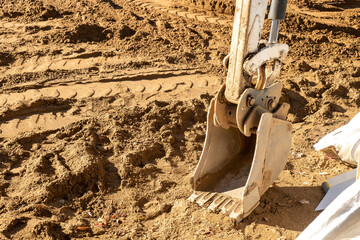 Backhoe scoop shovel attachment, used on backhoe for moving soil or gravel, is resting on the dirt...