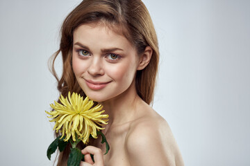 Portrait of a beautiful woman with a yellow flower on a light background cropped with Copy Space Model