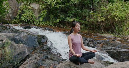 Woman do yoga with the waterfall background at waterfall