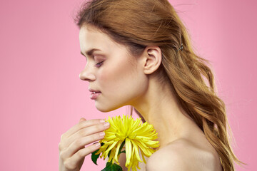 Portrait of a woman with yellow flowers on a pink background Makeup on the face