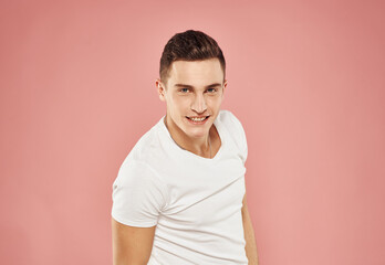 Handsome man in white t-shirt gesturing with hands studio pink background