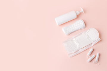 Tampons, feminine sanitary pads, liquid intimate soap on a pink background. Hygiene care during critical days. Menstrual cycle. Caring for women's health. Monthly protection, copy space