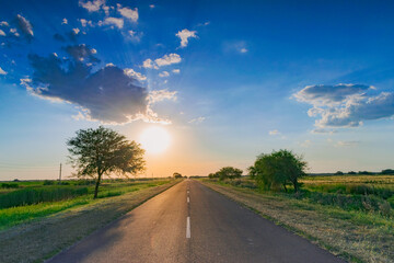 carretera solitaria al atardecer con el sol escondiéndose en el horizonte