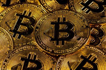 Close-up of gold Bitcoin coins on yellow background.