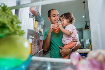 Young father and daughter open refrigerator at home looking for some food