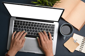 Overhead shot of female hands typing on laptop computer over black leather at workspace.
