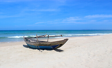 a fishing boat stands on the seashore, on a sandy beach against a blue sky