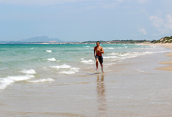 a man runs along the seashore on a sunny day