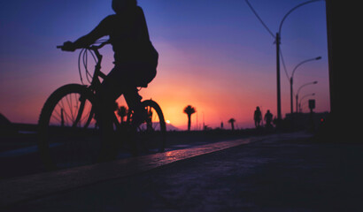 Fototapeta na wymiar Silhouette riding bicycle at sunset. Selective focus. Abstract Silhouette background concept.