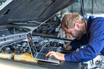 A Russian Male mechanic  with tablet pc computer making system diagnostic in car at workshop. car...