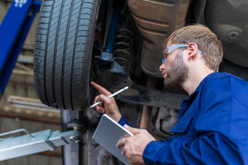 A male auto mechanic in uniform is examining a tire while working in auto service