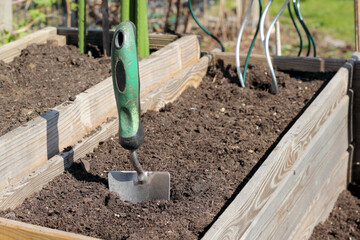 Gartenarbeit im Frühling / Handschaufel im Hochbeet