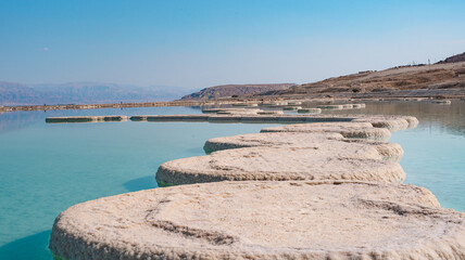 Fototapeta premium Original, small, stone islands in sea. Interesting seascape. Dead sea, Israel, vacation. Lot of salt, saltmarsh room, beautiful nature art. Close-up. View of bay.