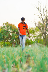 Indian farmer spraying pesticides in green onion field