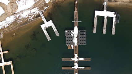4K Aerial drone photo of snowy lake dock 