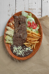 arrachera mexicana con enchiladas y papas fritas, platillo mexicano con chiles alrededor