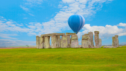 Hot air balloon flying over Stonehenge with cloudy sky - United Kingdom