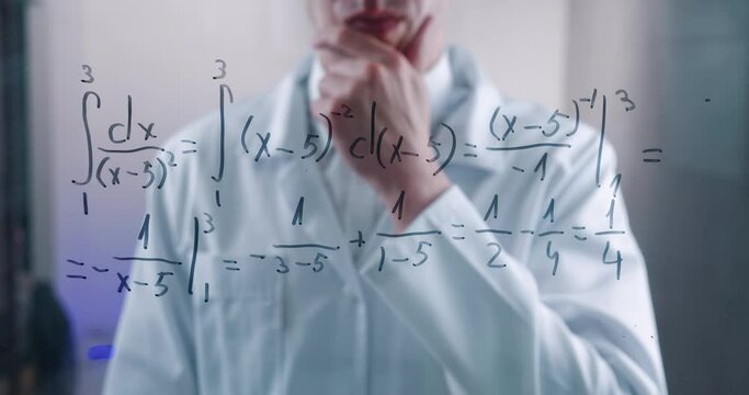 Man Scientist thinks over the solution of the integral equation, drawn on a glass board in a laboratory. The mathematician solves the problem.