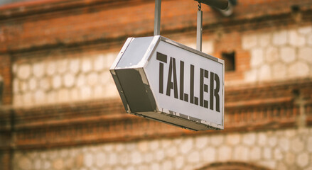 Sign hanging in the street indicating that there is a mechanical workshop, with the spanish word...