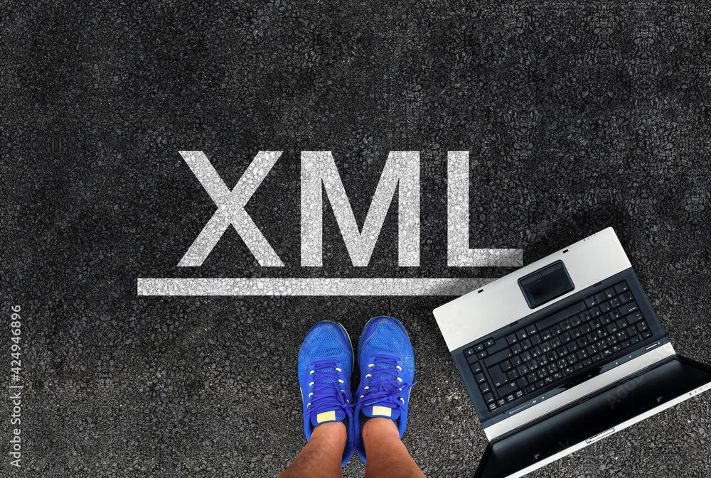 Aufkleber extensible markup language. man legs in sneakers standing next to laptop and word xml