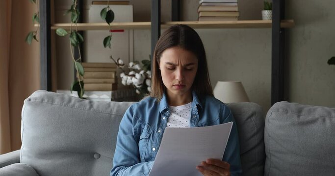 Woman sit on sofa read letter with bad news bank loan reject, female feel stressed about dismissal message, pay violation, unpaid tax penalty, eviction notice, bankruptcy, huge invoice for pay concept