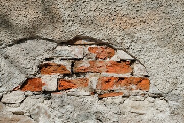 Alte Mauer mit abgebröckeltem Putz wo die Ziegel herausschauen