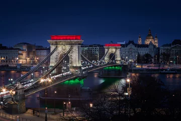 Photo sur Plexiglas Széchenyi lánchíd Budapest, Hungary - The world famous illuminated Szechenyi Chain Bridge (Lanchid) by night, lit up with national red, white and green colors, celebrating the 15th of March 1848 civic revolution day