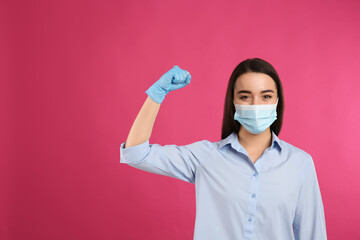 Woman with protective mask and gloves showing muscles on pink background, space for text. Strong immunity concept