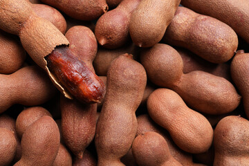 Delicious ripe tamarinds as background, closeup. Exotic fruit