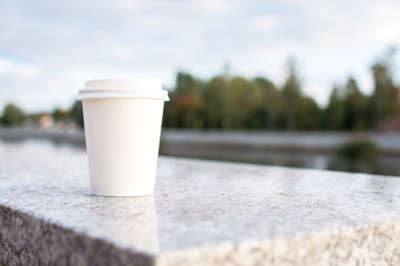 Paper cup on concrete table on street food festival trees on background selected focus