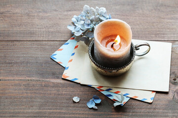 Vintage envelopes, candle and dried hortensia flowers on the table.