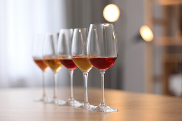 Different sorts of wine in glasses prepared for tasting on wooden table indoors